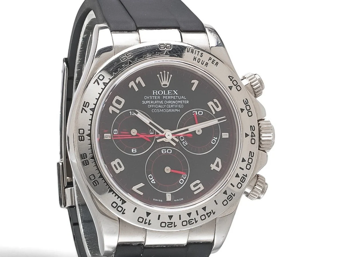 Close-up of a Rolex Daytona Racing dial and engraved tachymeter bezel: black dial, Arabic numerals, three counters with red hands and a red minute track