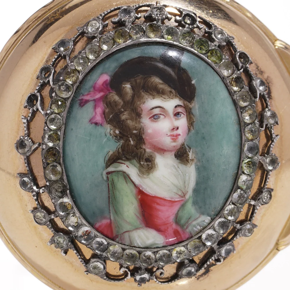 The back of an 18th-century gold pocket watch: a painted enamel portrait of a young woman framed in paste stones