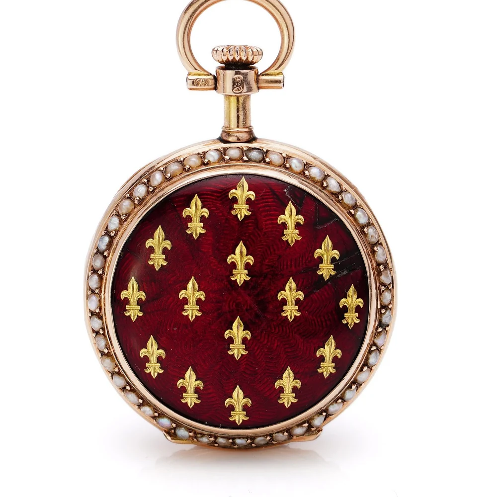 An antique 14ct rose gold fob watch with a red guilloche enamel cover, gold fleurs-de-lis and a beaded border