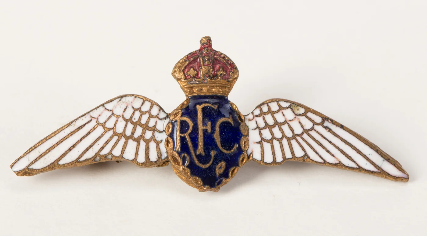 A First World War Royal Flying Corps sweetheart brooch in brass and enamel: white enamel wings either side of a blue oval with the letters RFC under a red enamelled crown