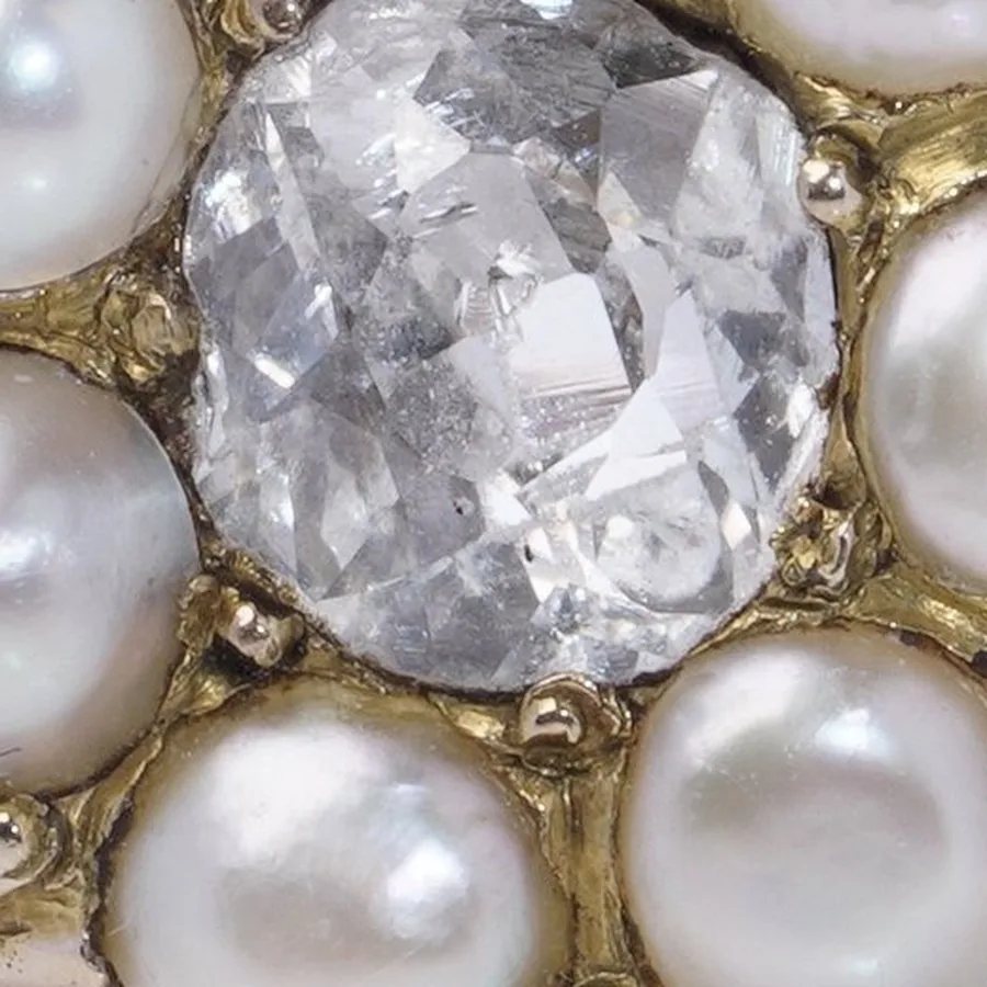 Close-up of an old mine cut diamond showing broad, slightly irregular hand-cut facets and a cushion outline