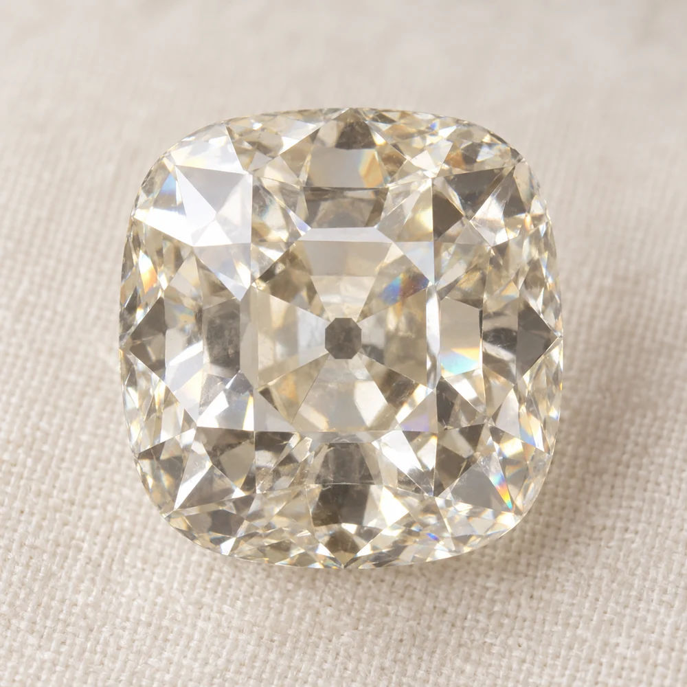 A loose old mine cut diamond face up, with a cushion outline, broad facets and an open culet showing as a dark dot at the centre