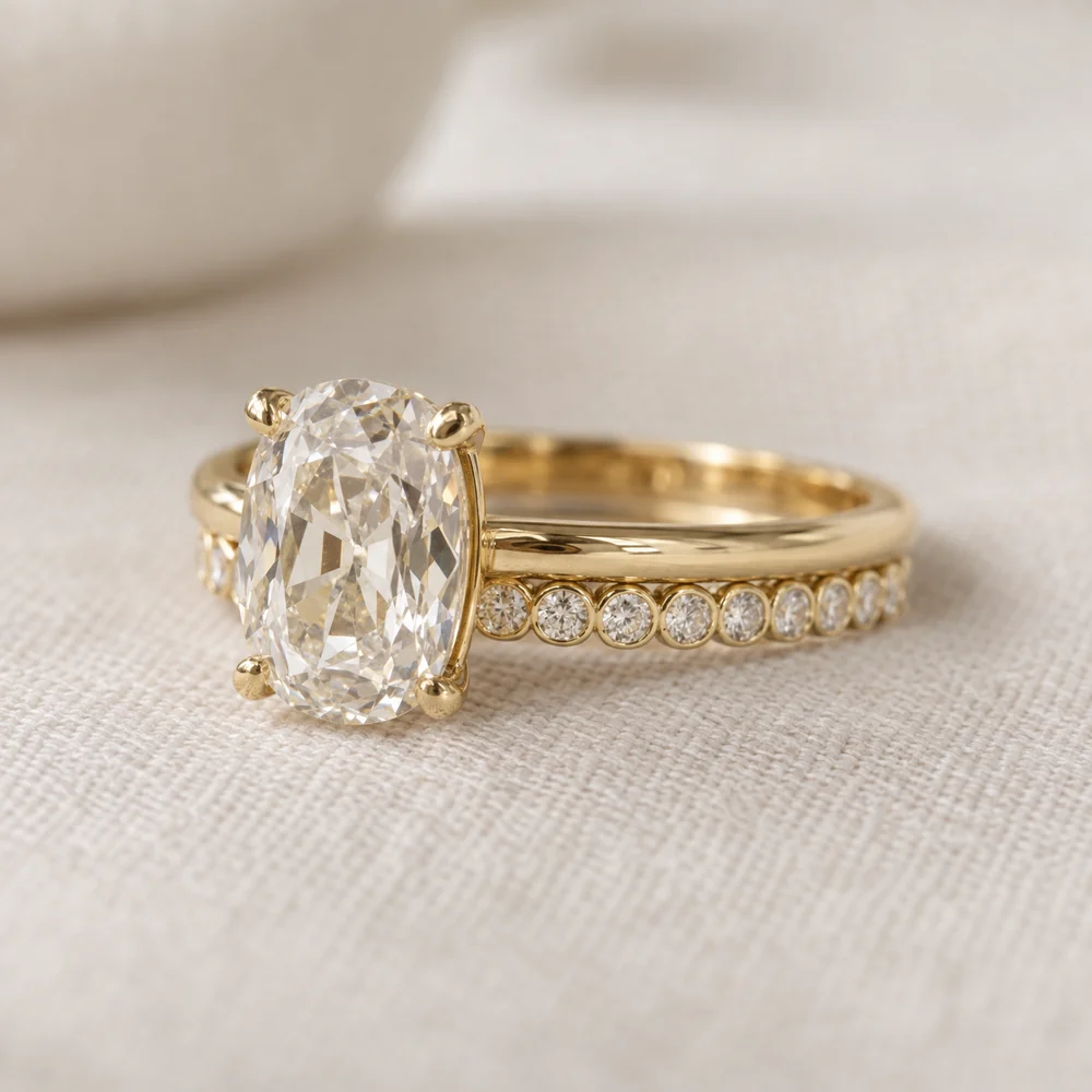 Illustration of an elongated old mine cut engagement ring in yellow gold beside a flush yellow gold wedding band of bezel-set round diamonds