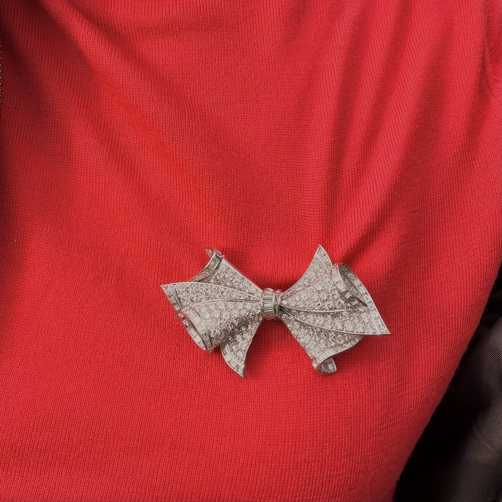 Adler 18KT white gold diamond bow double clip brooch worn on a red knit