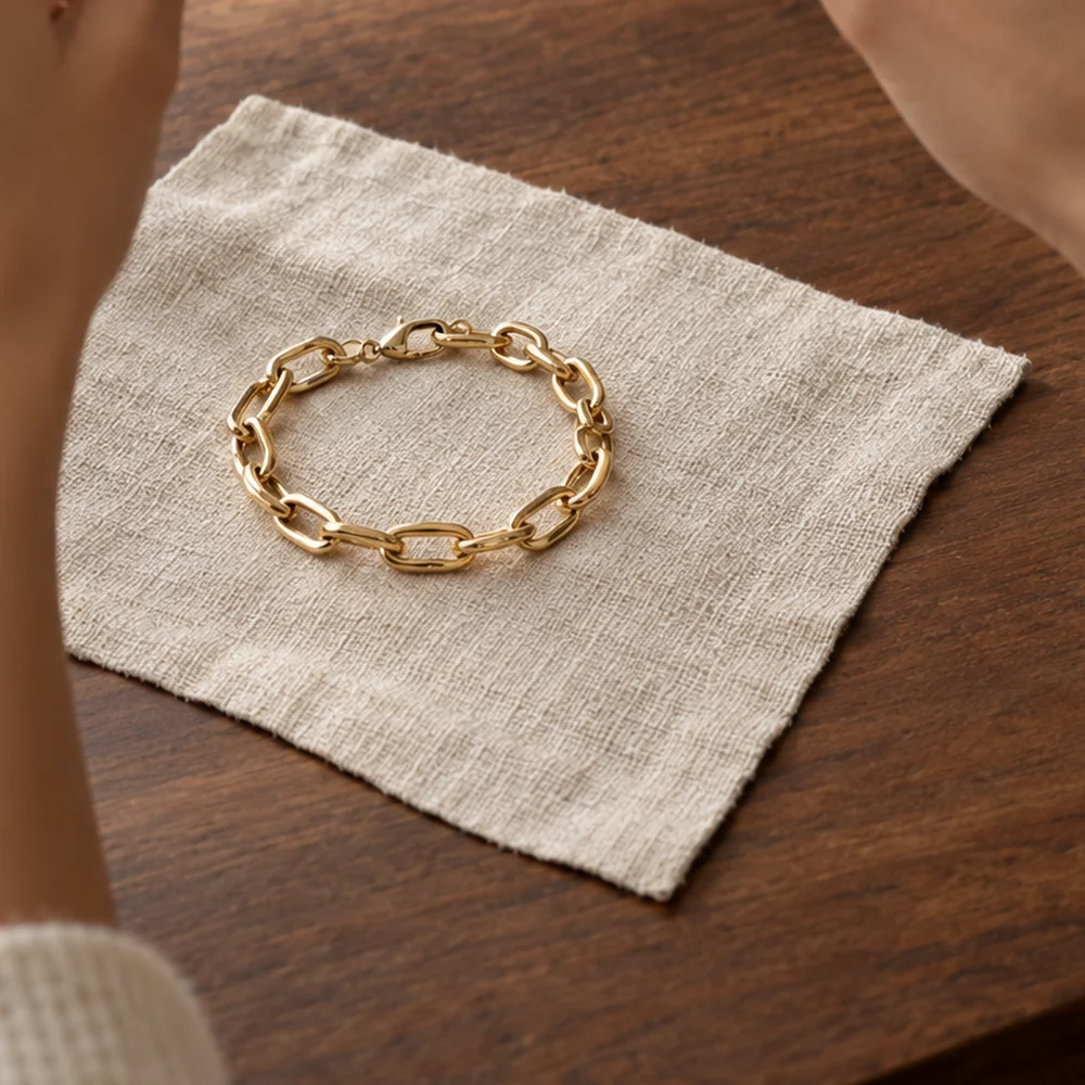 A gold link bracelet laid on a square of linen on a walnut table, ready to be photographed