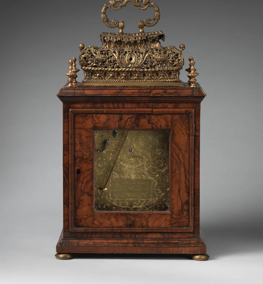 The back of a walnut bracket clock by John Andrews, London, about 1690, with its engraved brass backplate behind the glazed rear door