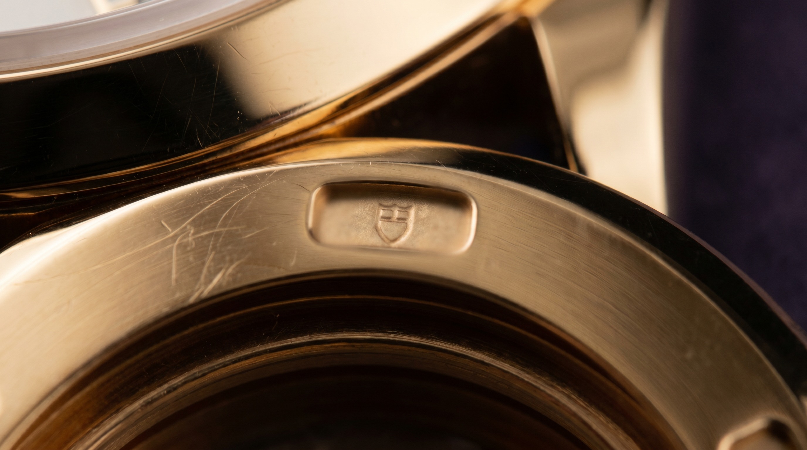 Macro of a hallmark date-letter punch in a shaped shield on a gold watch case