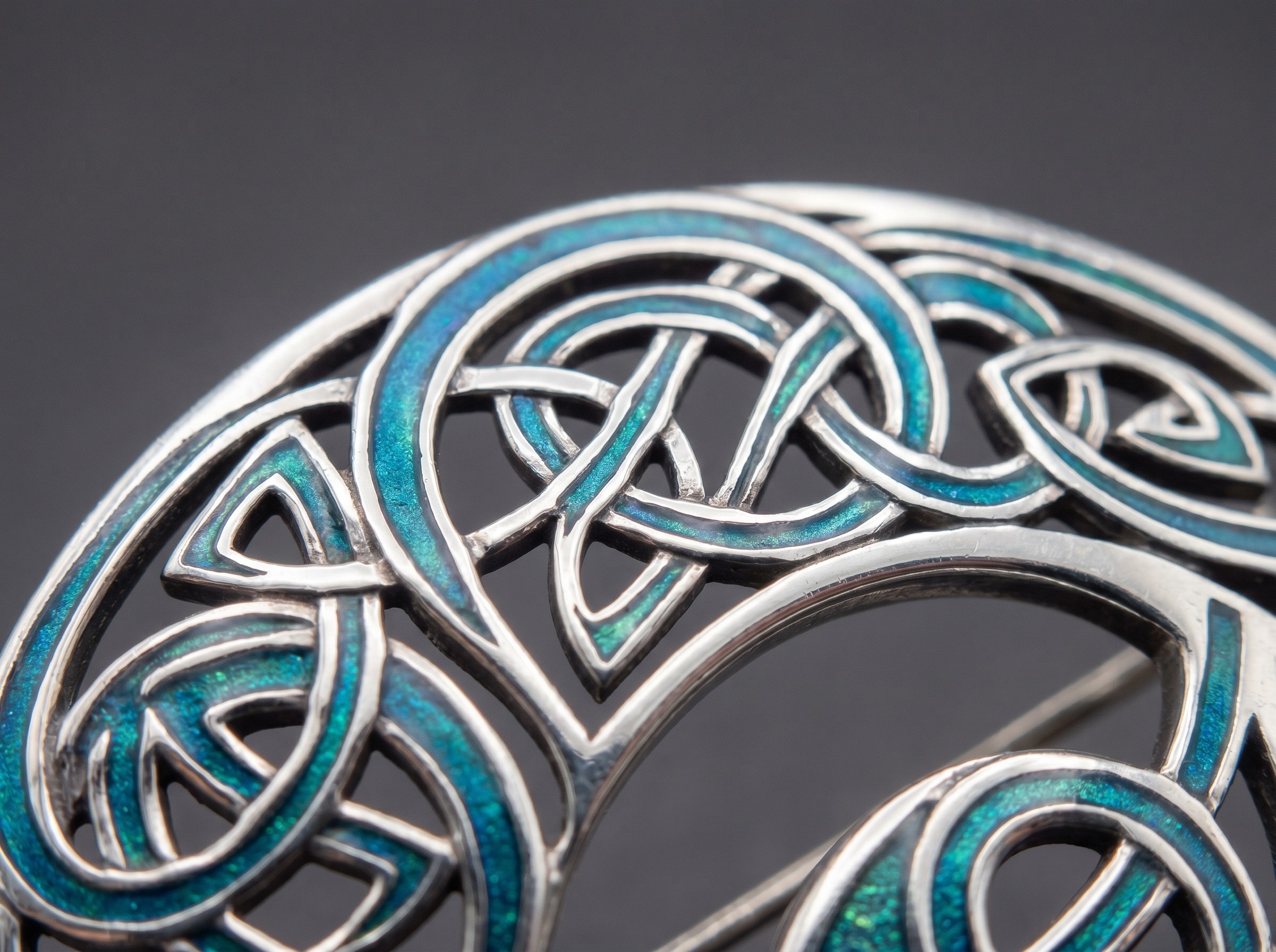 Celtic entrelac knotwork and blue-green enamel on Liberty Cymric silver in the Archibald Knox style — macro