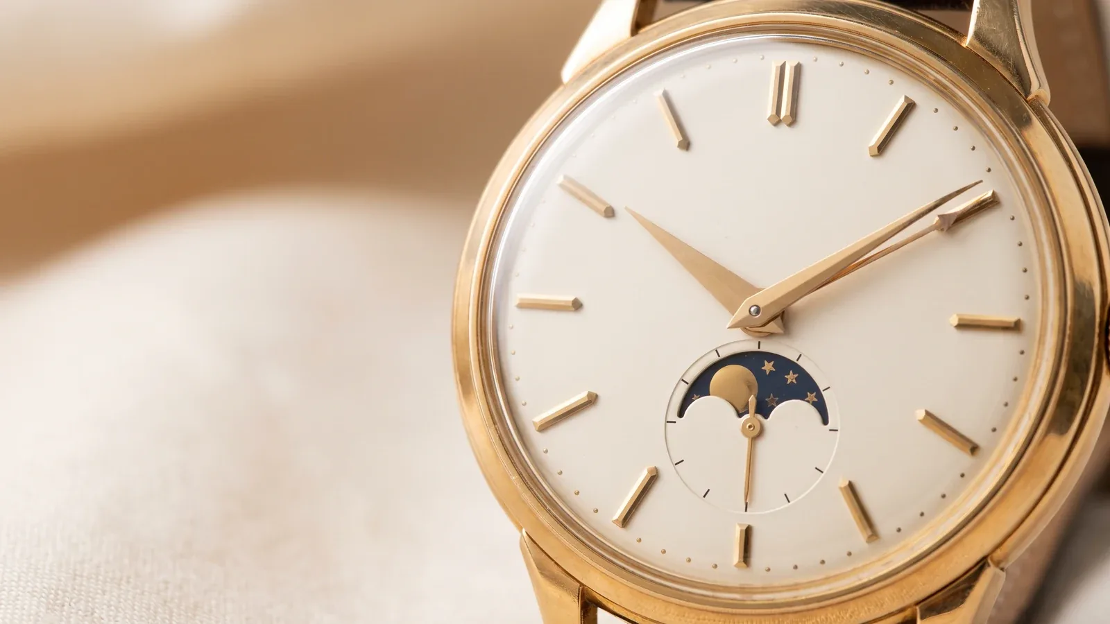 A vintage gold triple-calendar moonphase wristwatch dial in a close crop, plain dial with no logo and no lettering