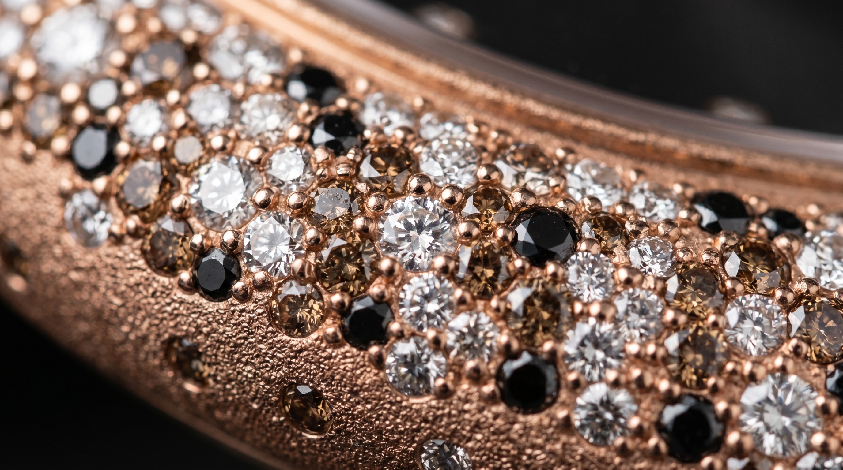 Close-up of brown white and black diamonds scattered in rose gold