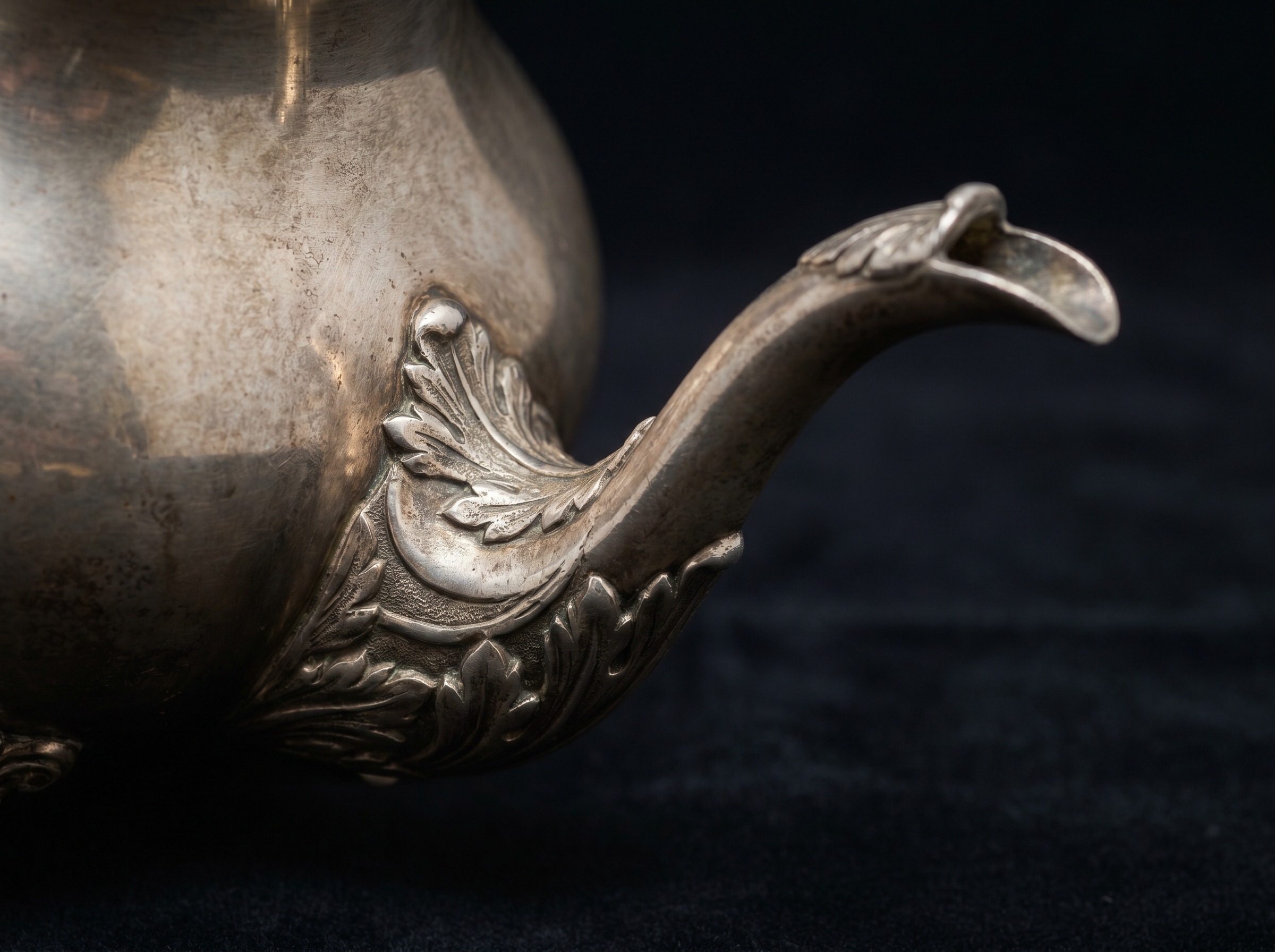 Cast spout with applied leaf ornament on an antique English sterling silver coffee pot — extreme macro