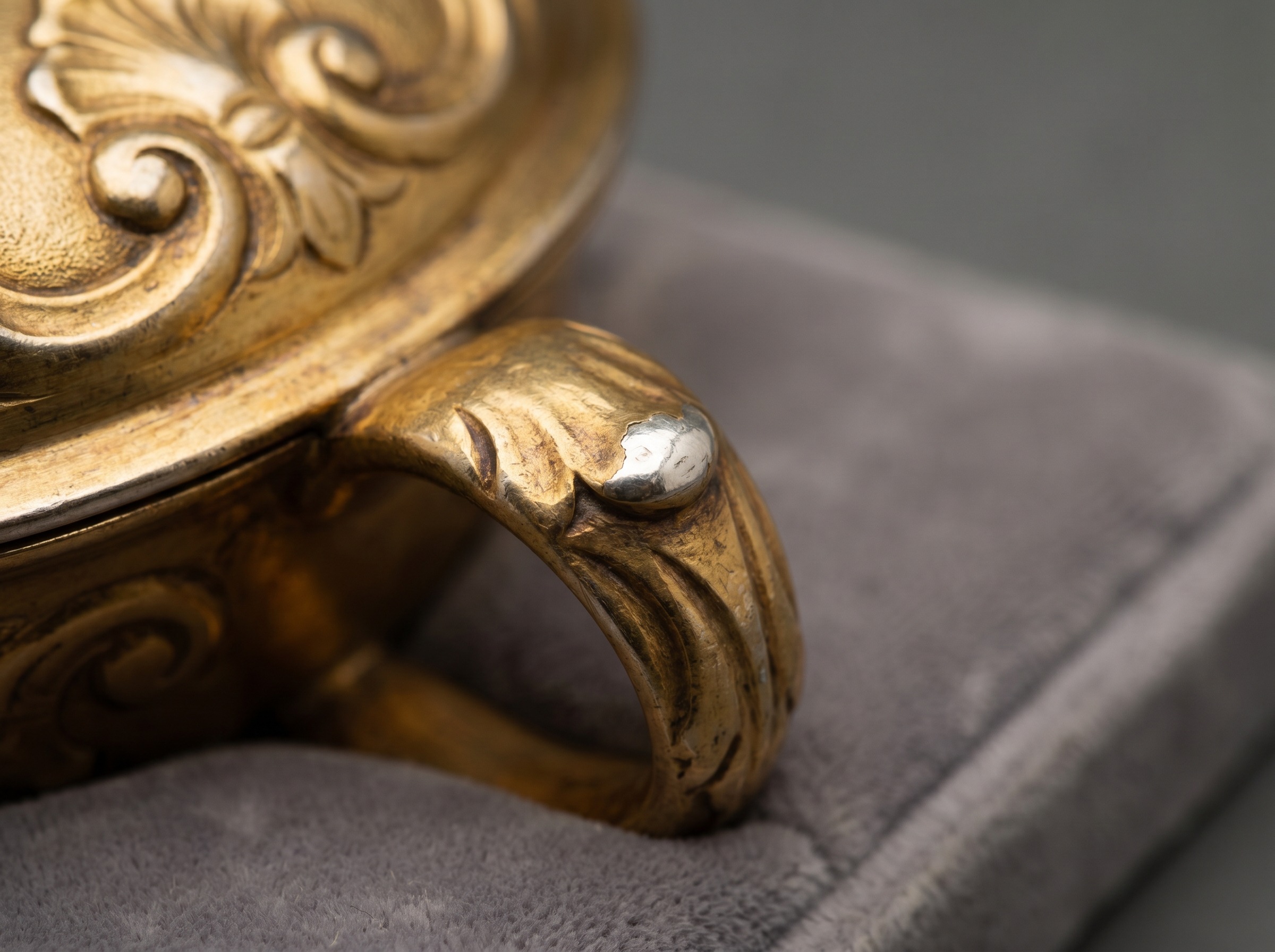 Worn point on silver-gilt vermeil showing white silver under gold gilding — macro