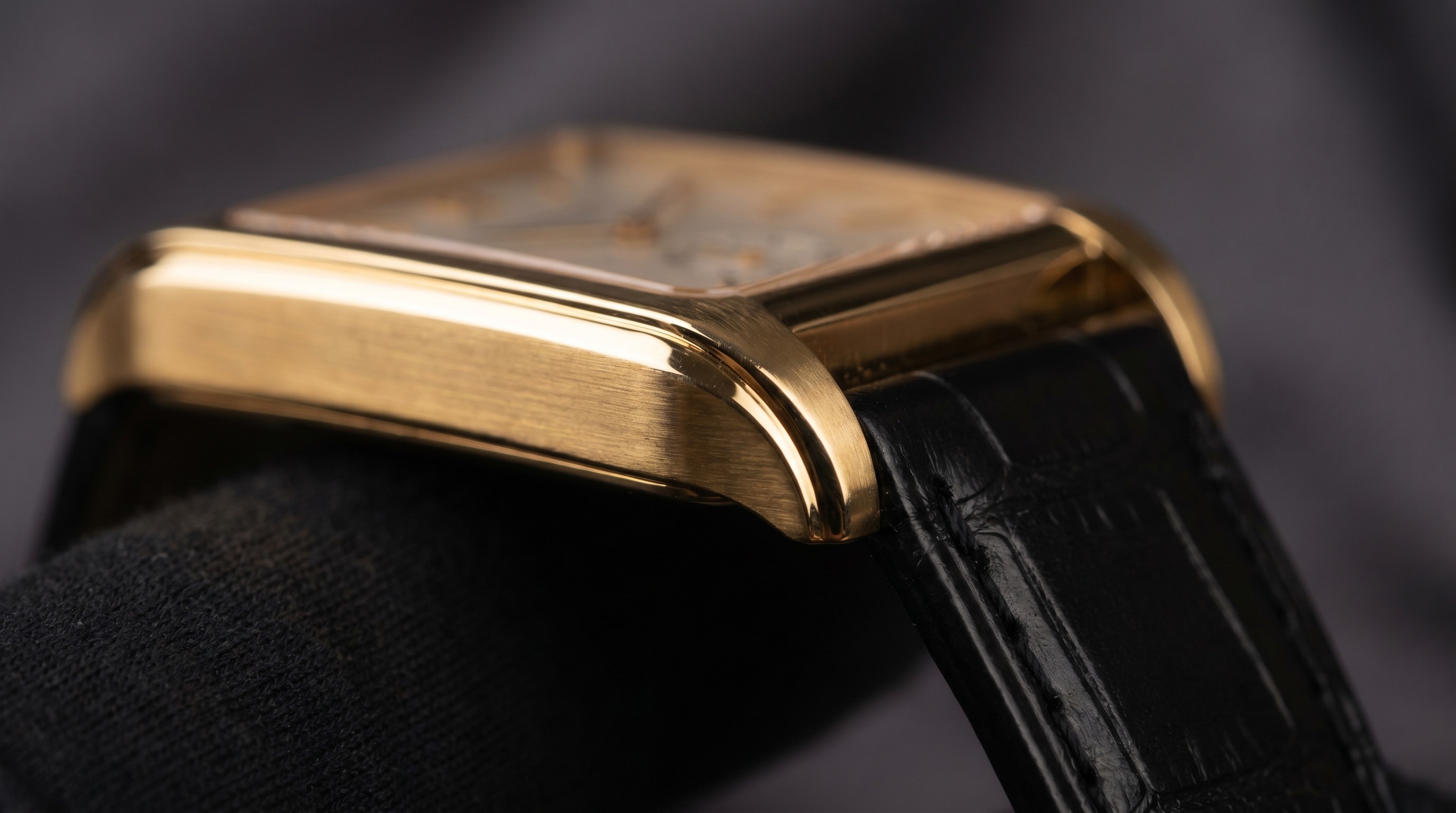 Side view of a gold Cartier Tank case showing the flat brancard side rails flowing into the strap