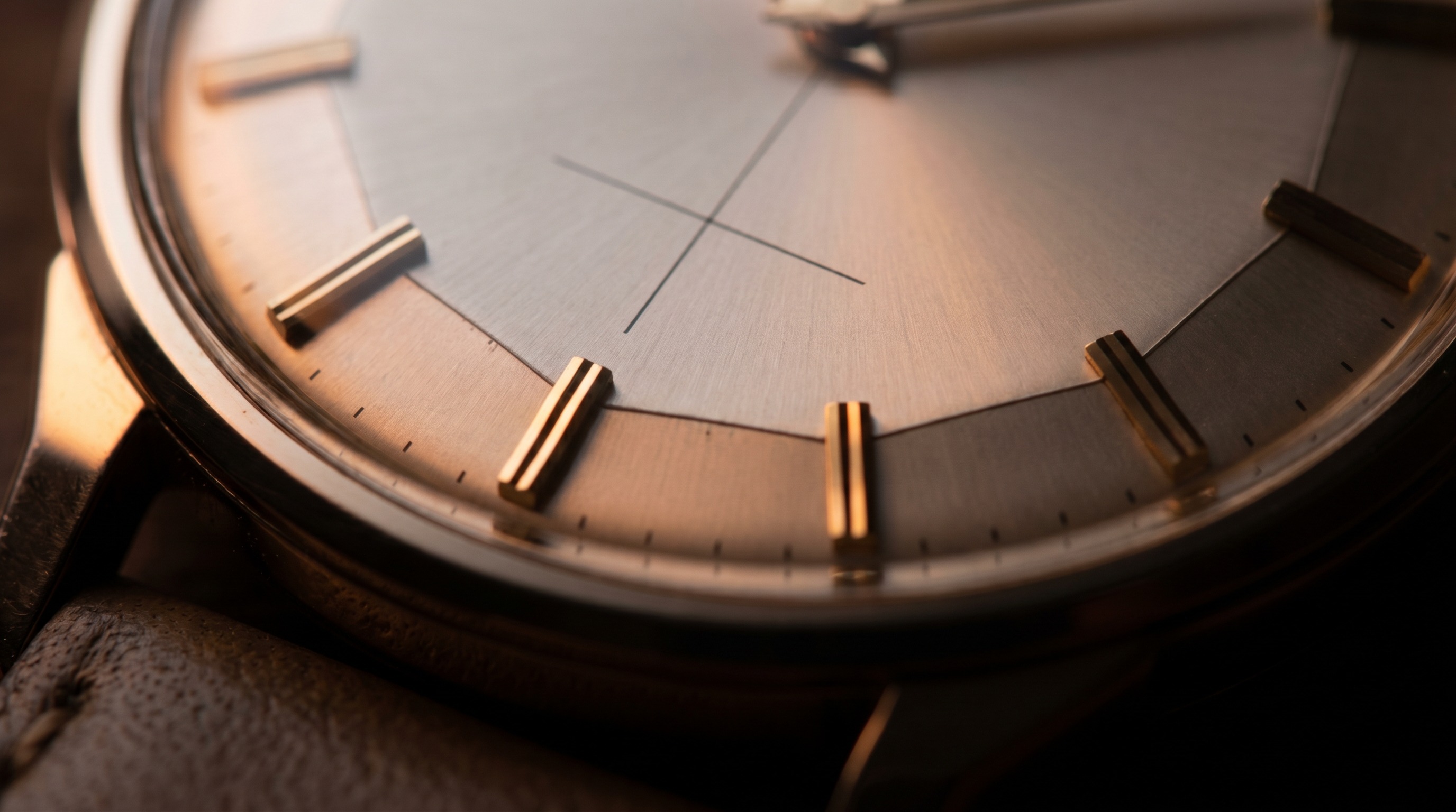 Macro of a multi-faceted pie-pan watch dial with applied gold markers