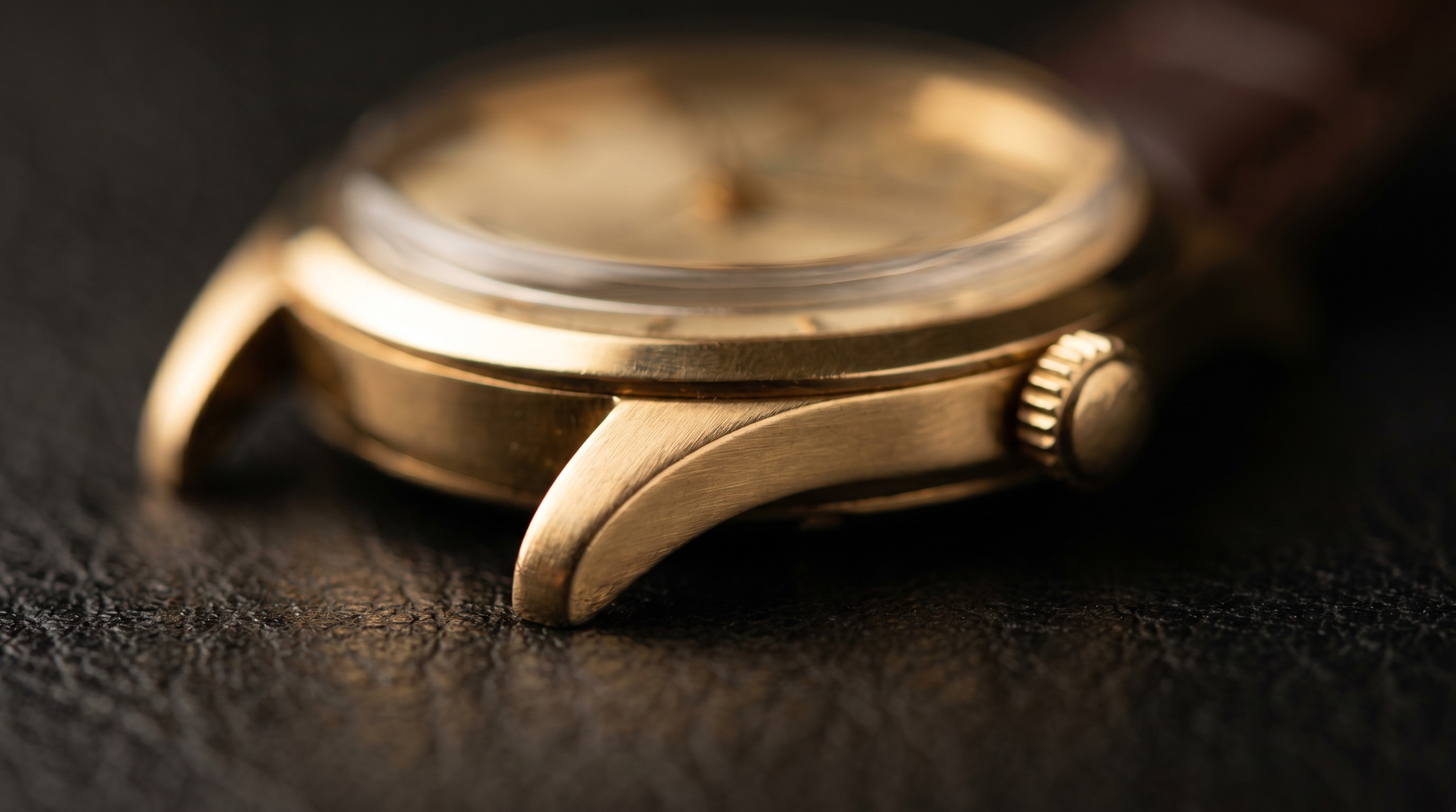 Macro of the warm yellow gold case, lugs and crown of a vintage wristwatch